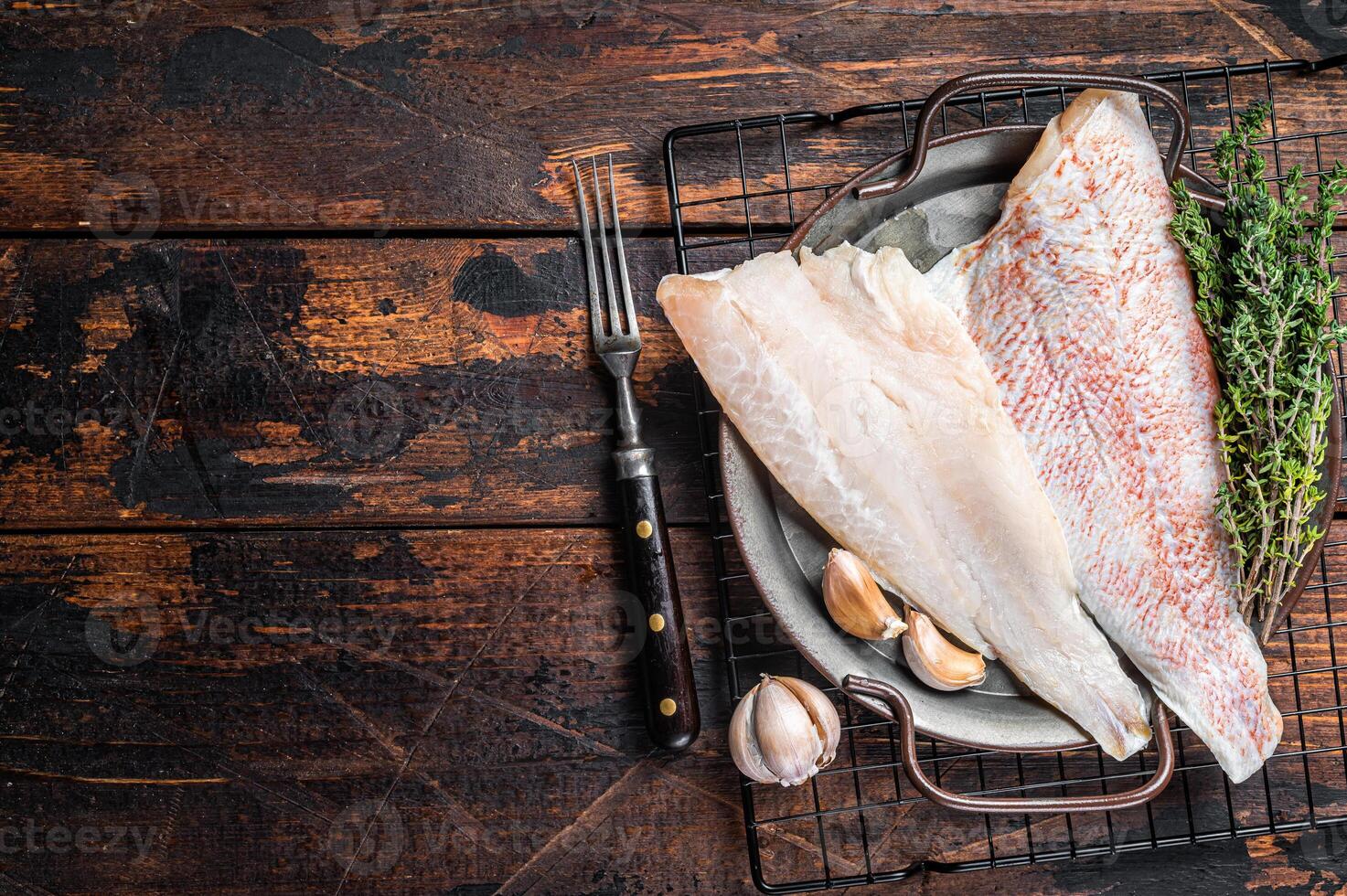 Raw red perch fillet, redfish fish meat in a steel tray. Wooden background. Top view. Copy space photo