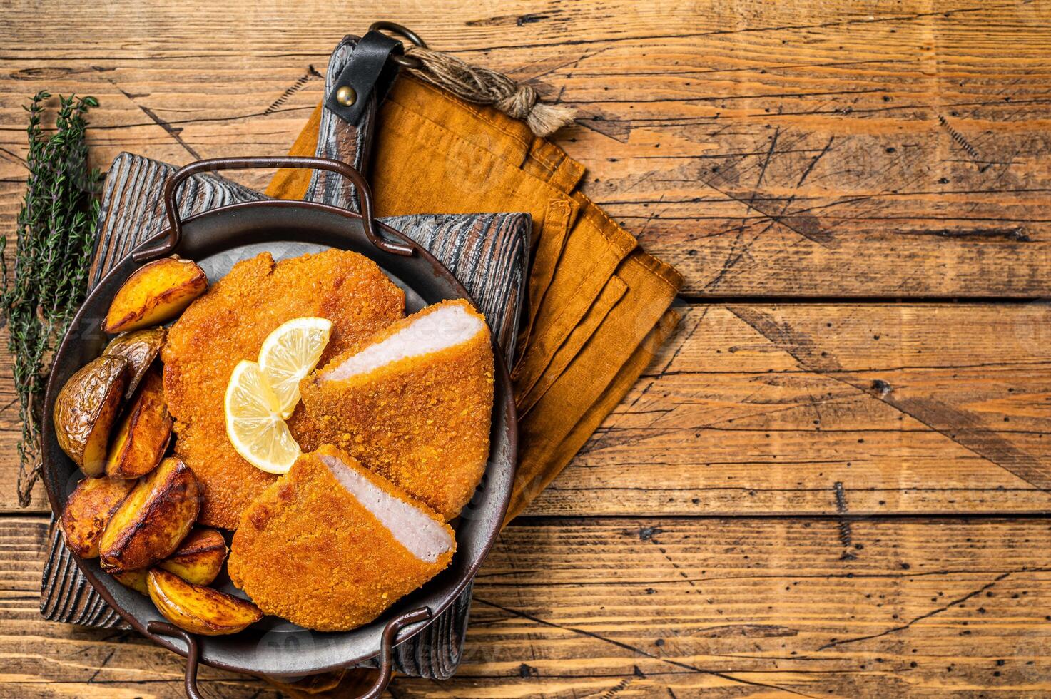 Delicious crispy pork schnitzel with fried potato wedges. Wooden background. Top view. Copy space photo
