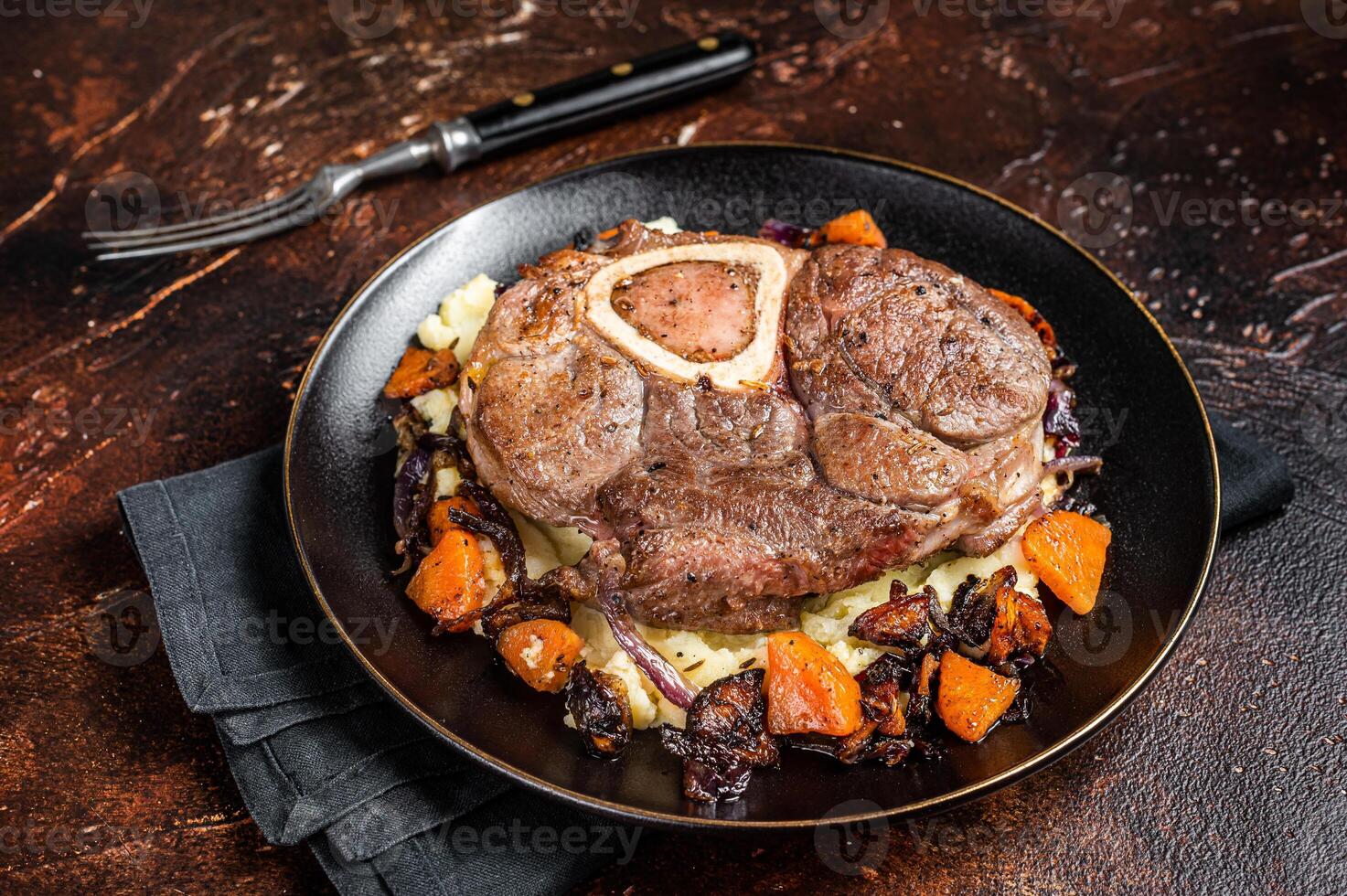 Osso buco cross cut veal shank with mashed potato on a plate. Dark background. Top view photo