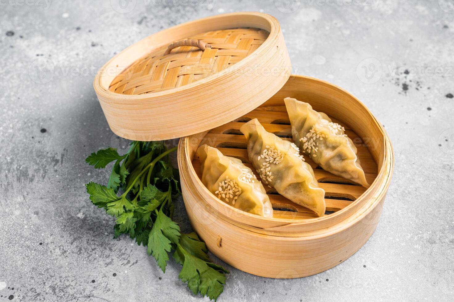 Steamed Jiaozi Chinese Dumplings with meat and vegetables in bamboo steamer. grey background. top view photo