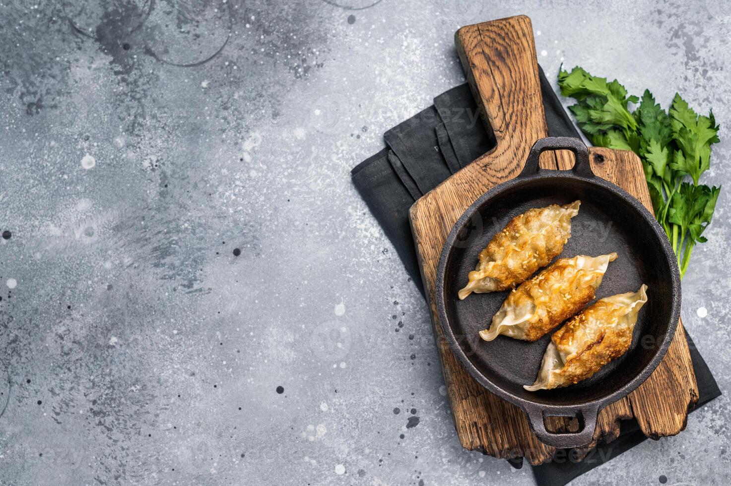 Fried Korean Dumplings with meat and vegetables in skillet. grey background. top view photo