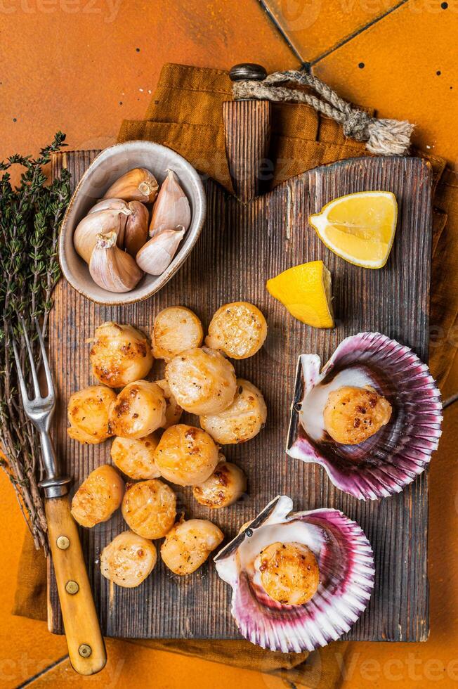 Seared Scallops fillets on a wooden board ready for eat. Orange background. Top view photo