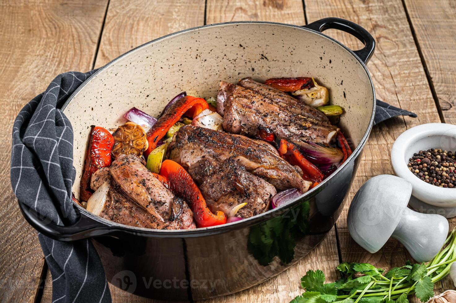 Roasted slow cooked lamb shanks with vegetables and herbs. Wooden background. Top view photo