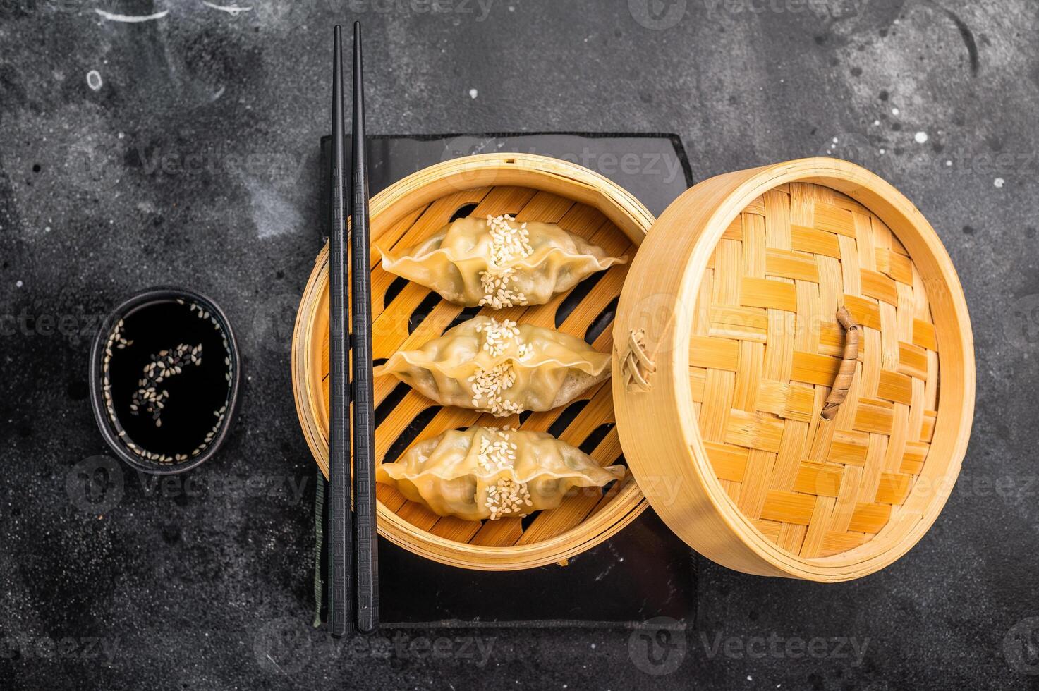 Steamed Korean Dumplings with pork meat and vegetables in bamboo steamer. black background. top view photo