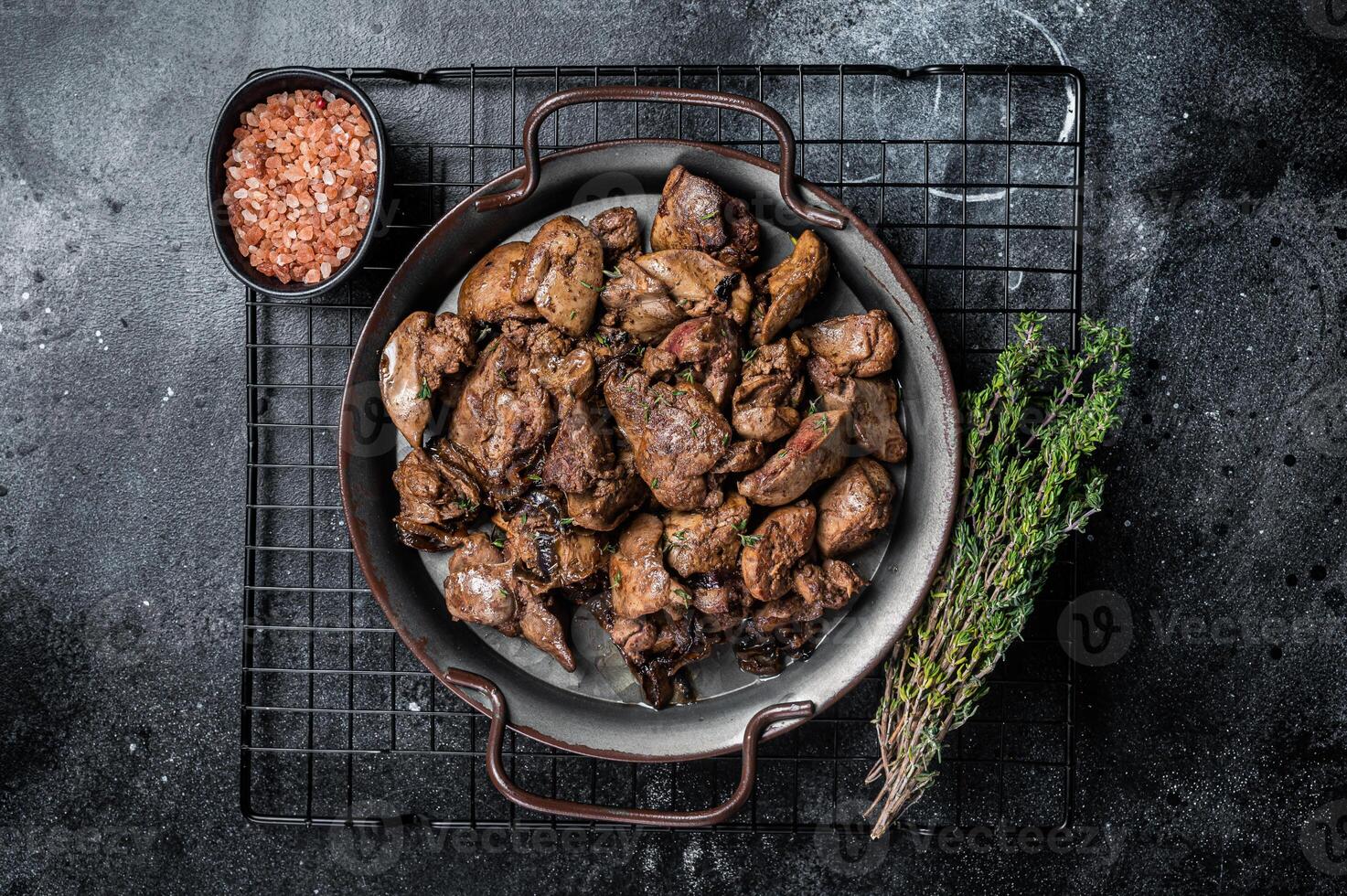 Fried chicken liver with onions and herbs. Black background. Top view photo