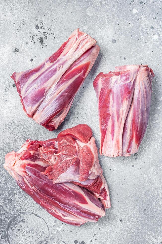 Uncooked Raw lamb shanks, mutton meat on kitchen table. Gray background. Top view photo