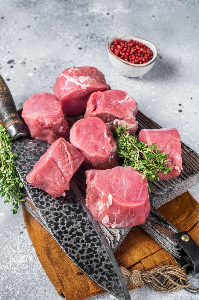 Fresh Raw pork tenderloin medallions steaks on a wooden cutting board. Gray background. Top view photo