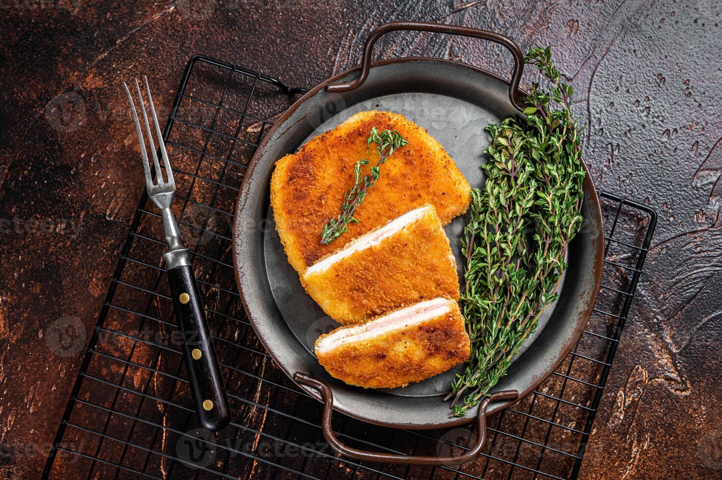 Cordon bleu chicken fillet cutlet with ham and cheese. Dark background. Top view photo