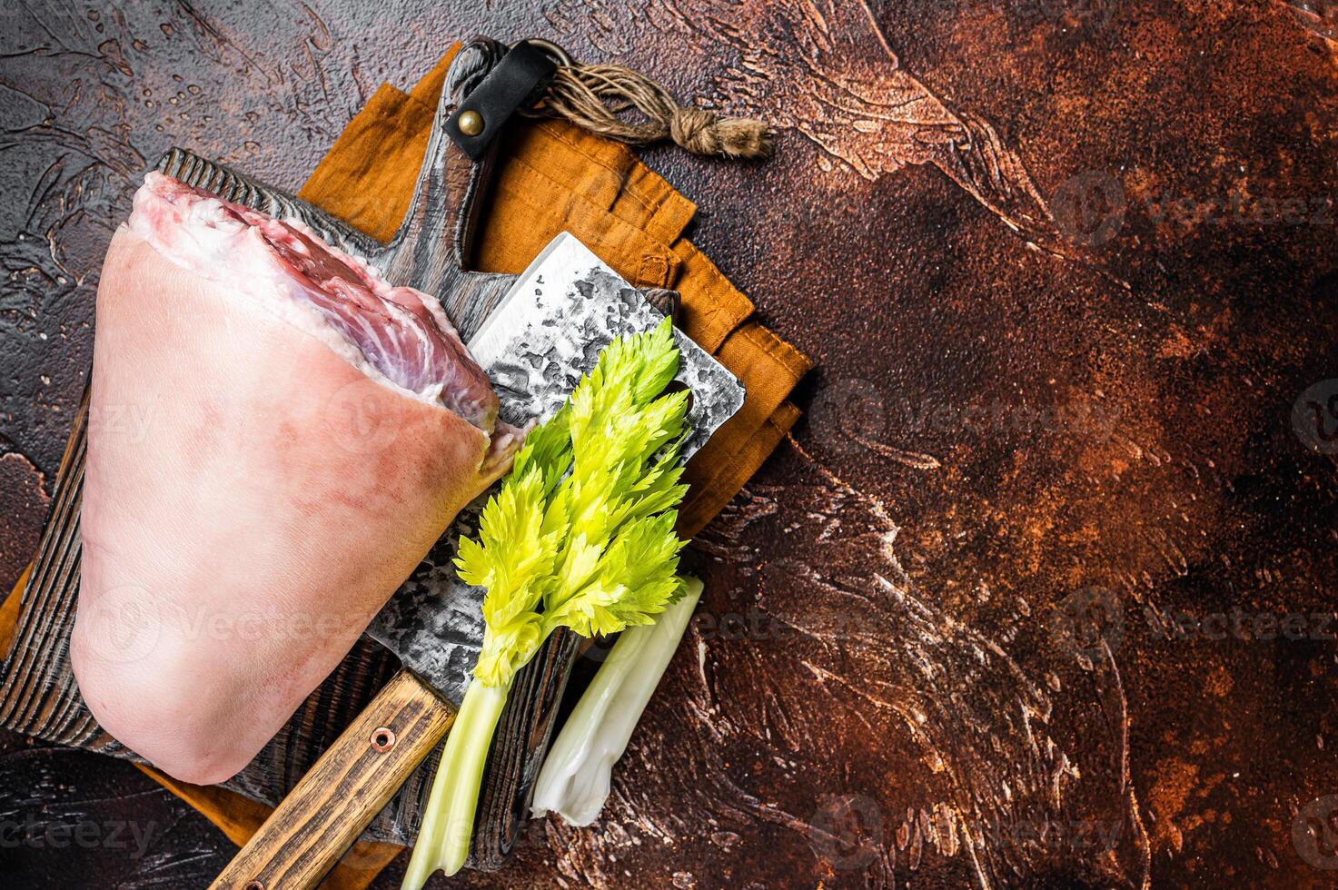 Fresh Raw pork shank knuckle on a butcher board with herbs for cooking. Dark background. Top view. Copy space photo