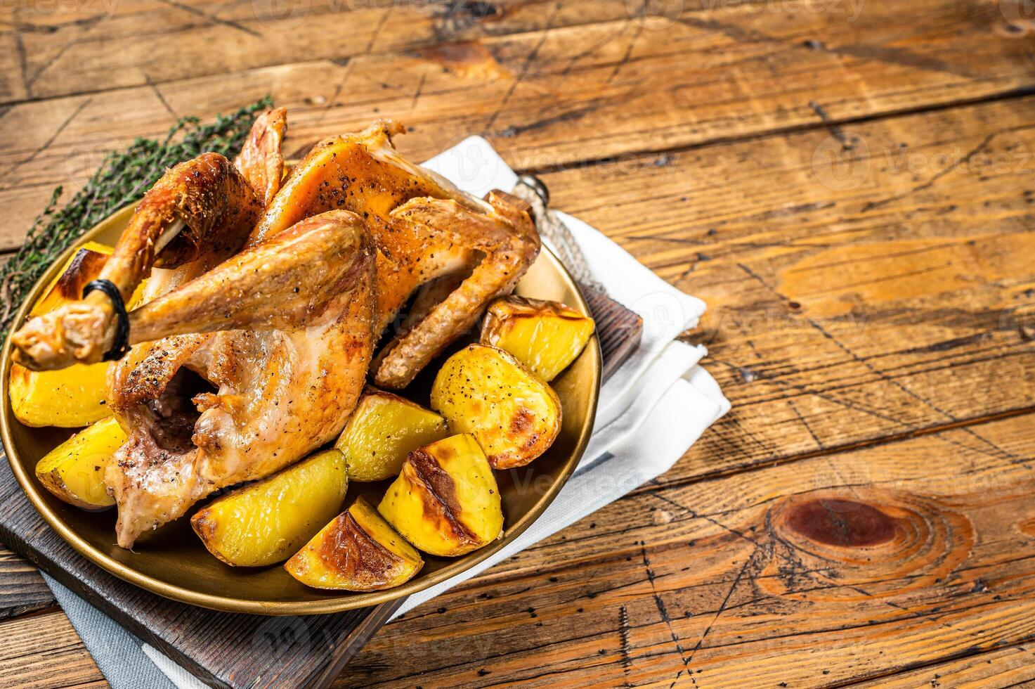 Roasted guinea fowl with herbs and potato, cooked farm eco bird. Wooden background. Top view. Copy space photo