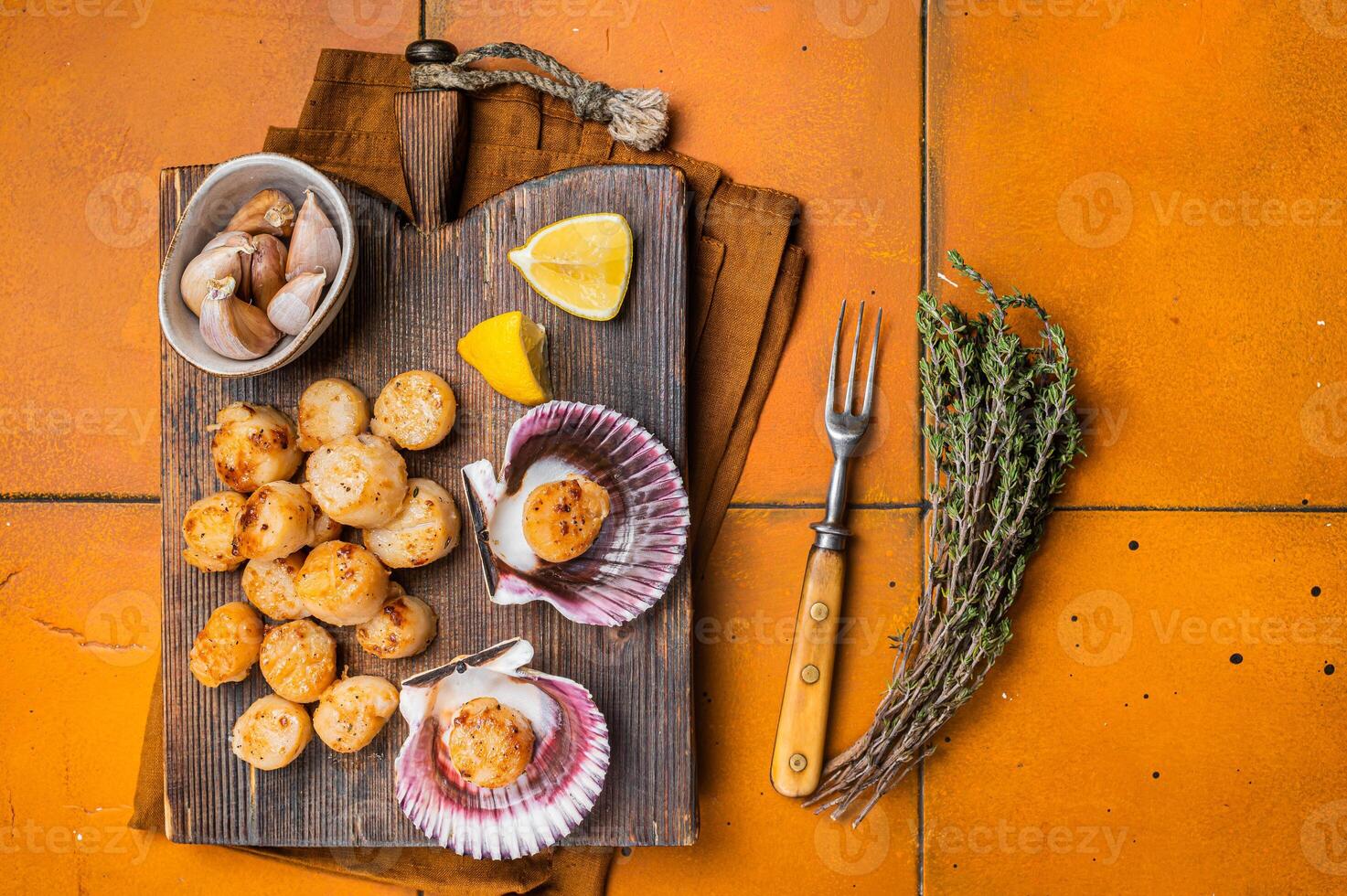 Seared Scallops fillets on a wooden board ready for eat. Orange background. Top view photo