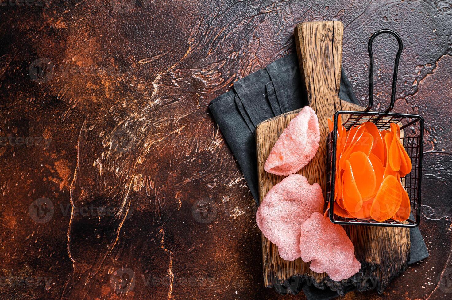 Cooking raw kerupuk or prawn shrimp crackers, chips. Asian fastfood. Dark background. Top view. Copy space photo