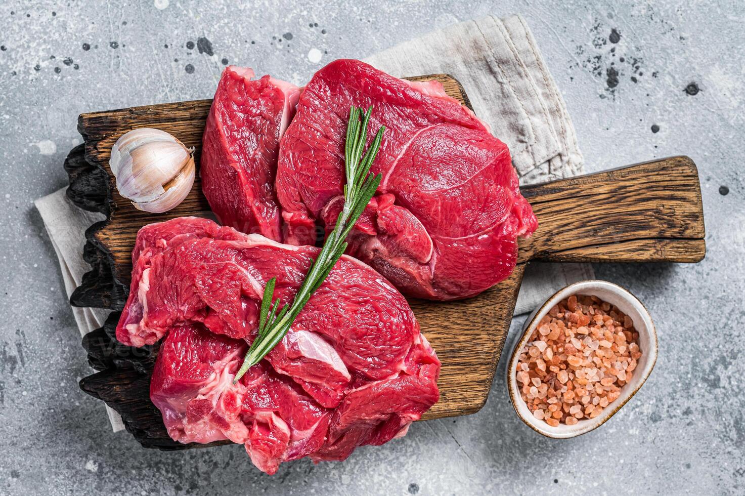 Uncooked Raw Lamb chop leg steaks on cutting board. Gray background. Top view photo