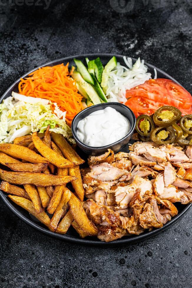 Shawarma Doner kebab on a plate with french fries and salad. Black background. Top view photo