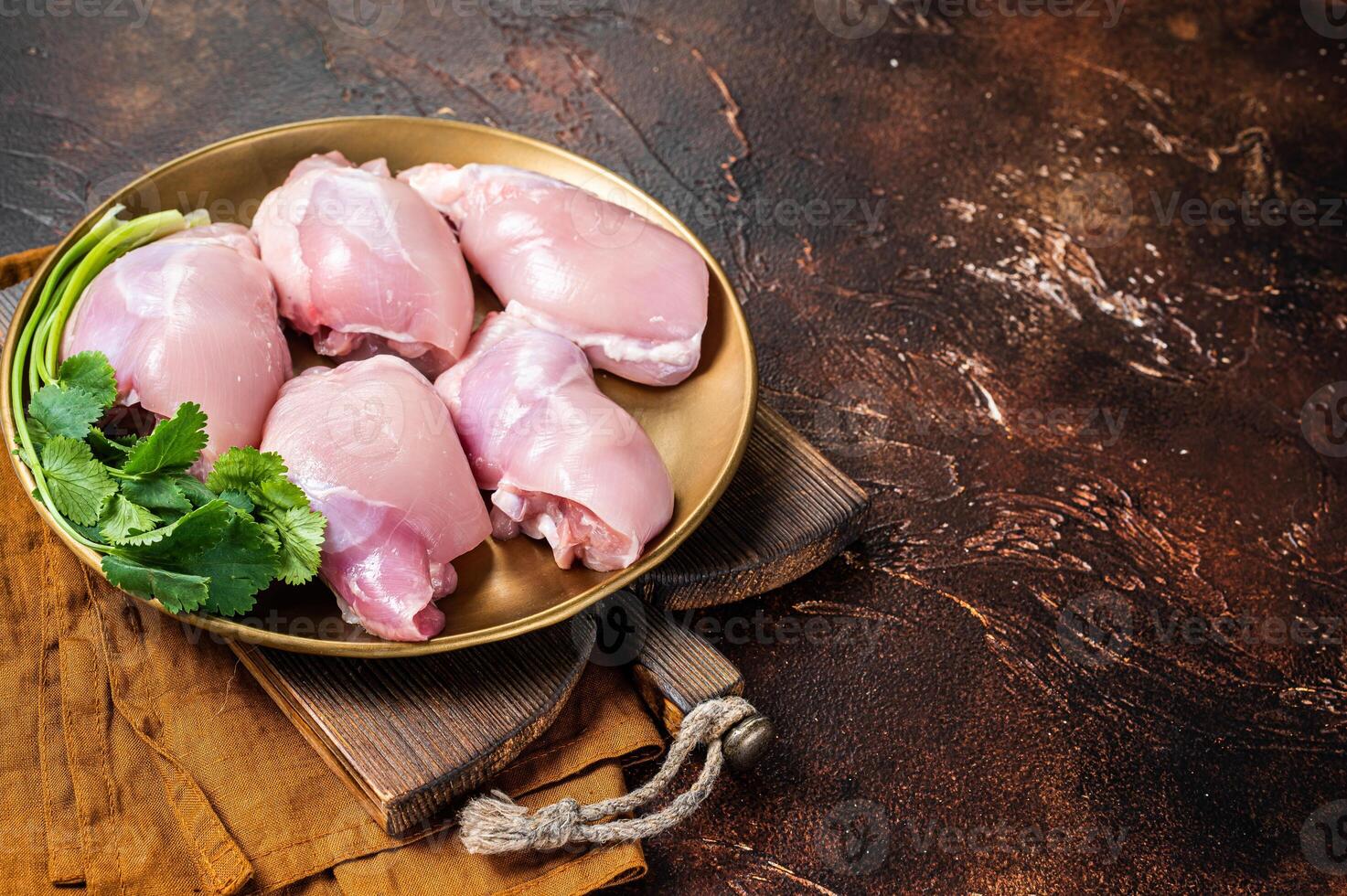 Free range Raw Boneless and skinless Chicken leg thigh fillet with spices. Dark background. Top view. Copy space photo