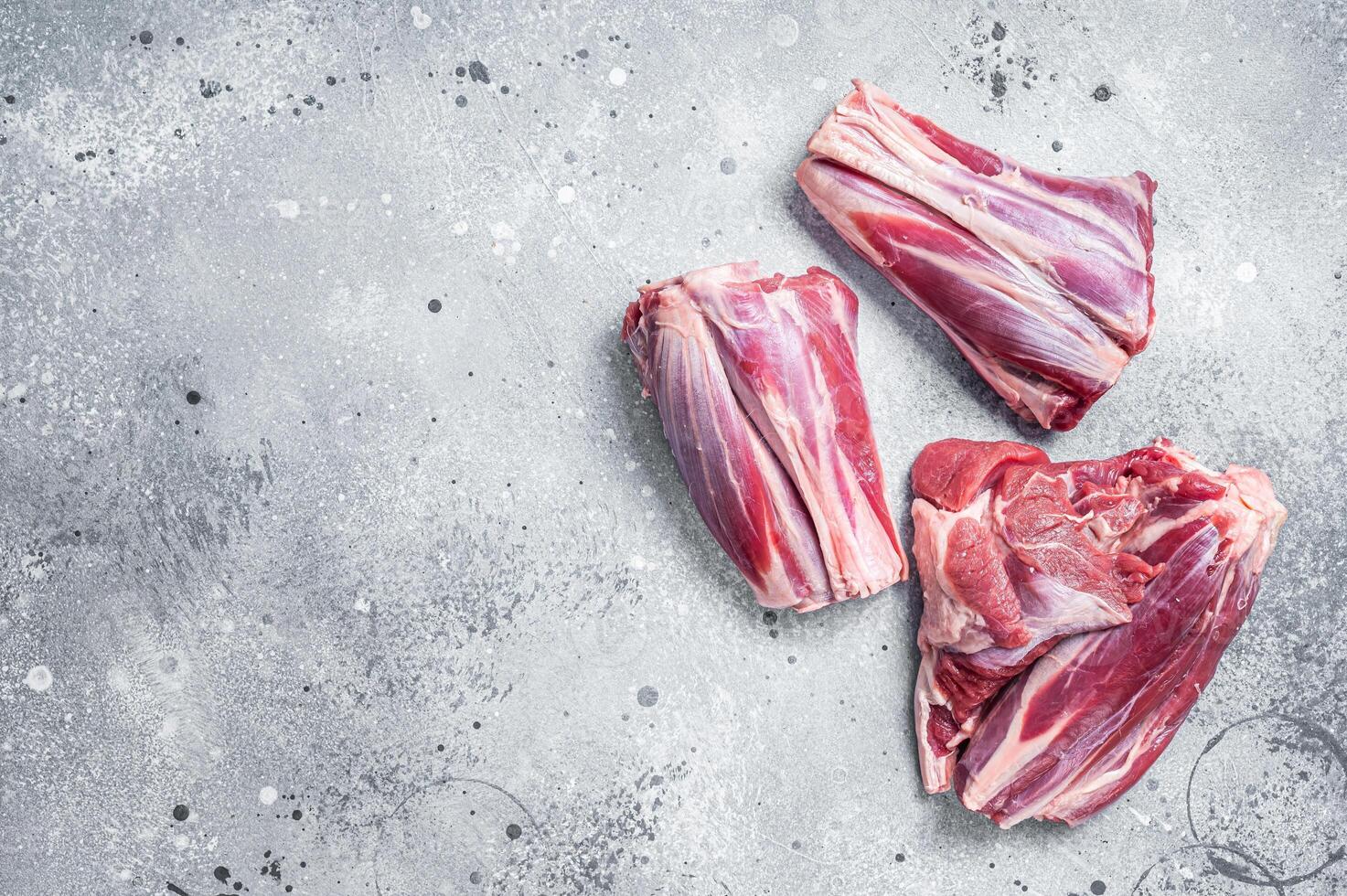 Uncooked Raw lamb shanks, mutton meat on kitchen table. Gray background. Top view. Copy space photo