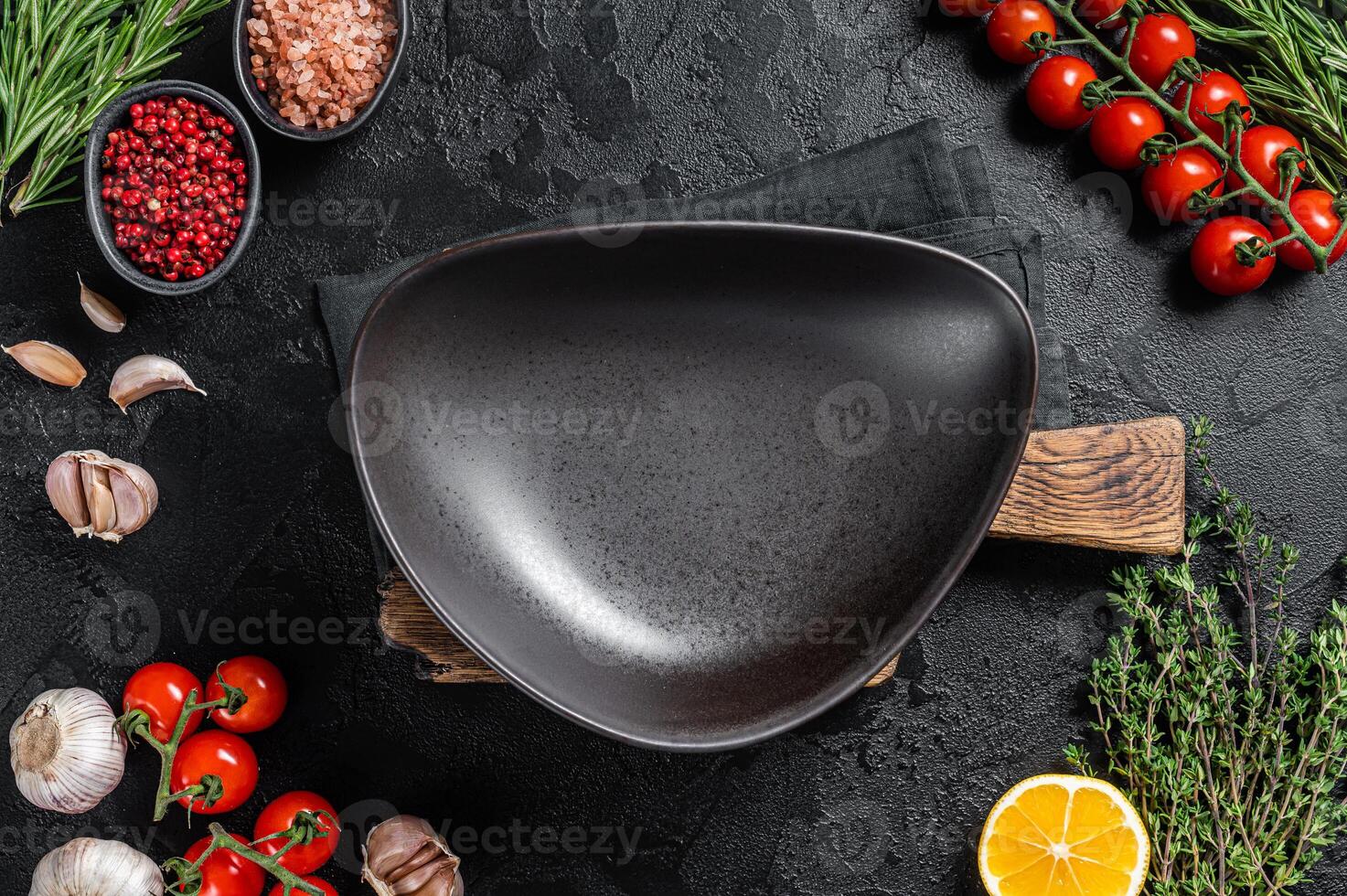 Healthy eating vegan food concept background with empty plate and fresh seasoning, herbs and ingredients. Black background. Top view. Copy space photo