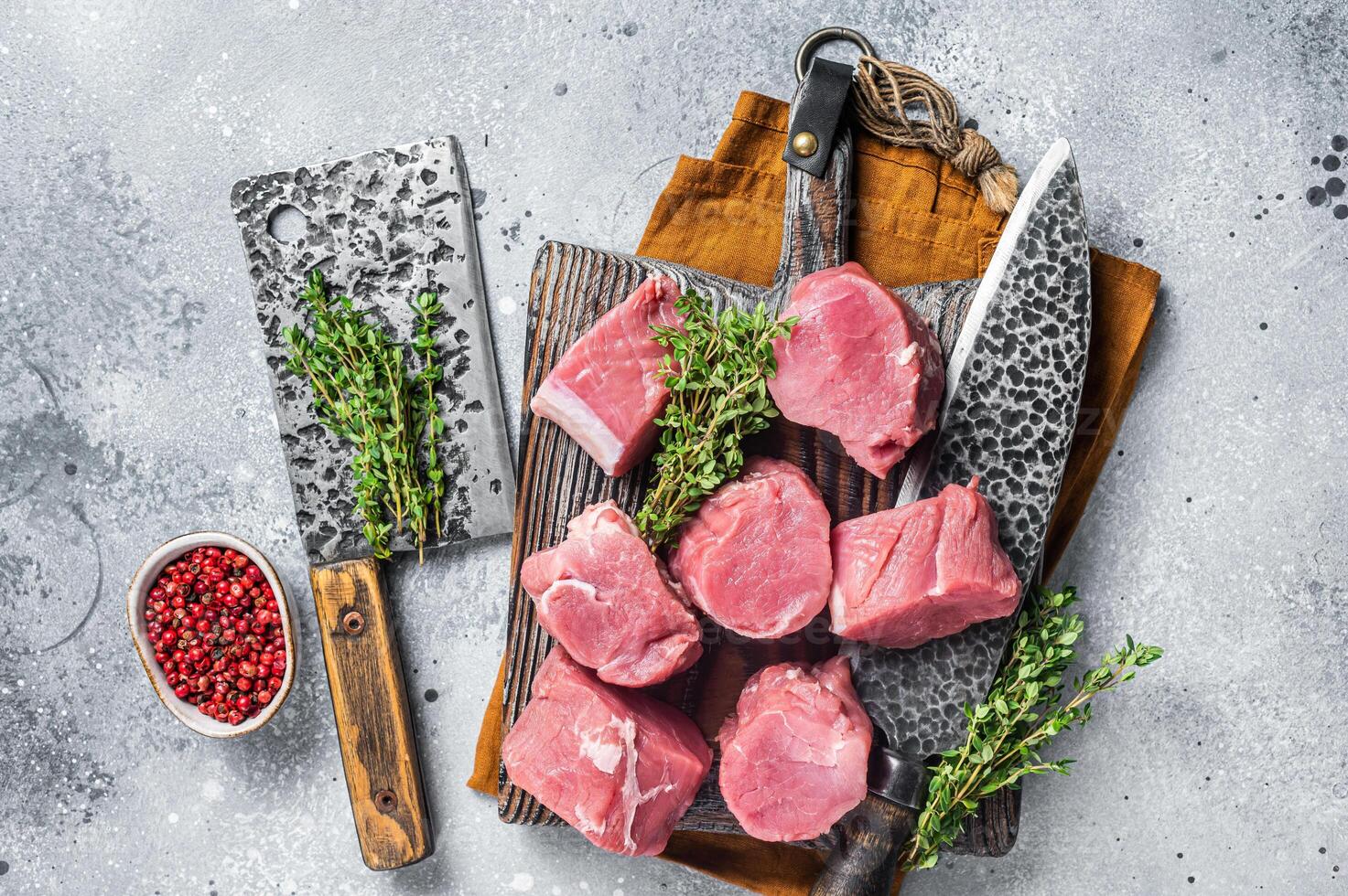 Fresh Raw pork tenderloin medallions steaks on a wooden cutting board. Gray background. Top view photo