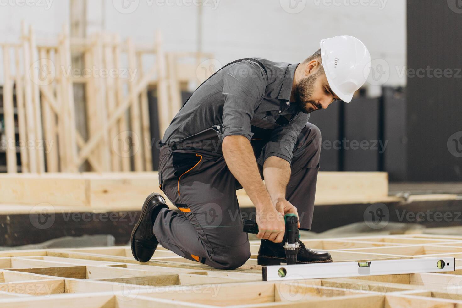 Construction worker building wooden frame using level tool and drill photo