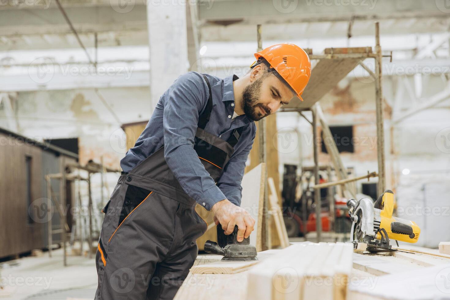 Carpenter sanding wooden plank in modular building factory photo