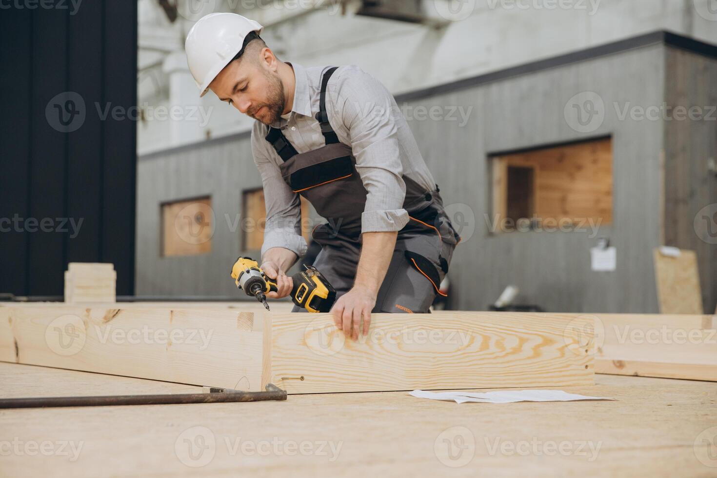 Carpenter using cordless drill assembling wooden frame for modular building photo