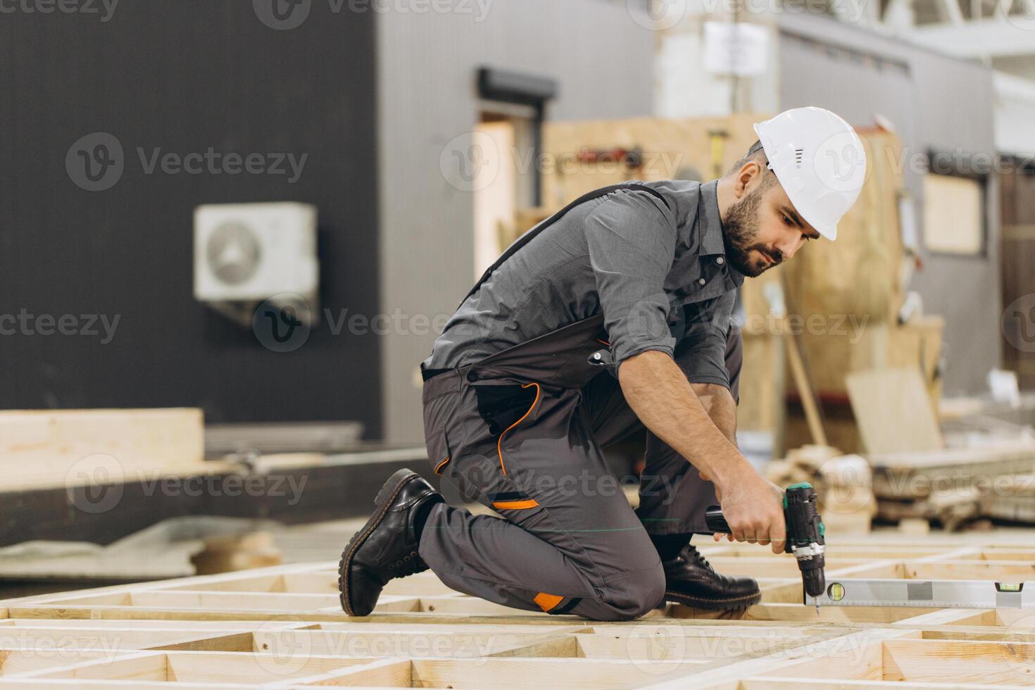 Carpenter building wooden frame house using electric screwdriver in workshop photo