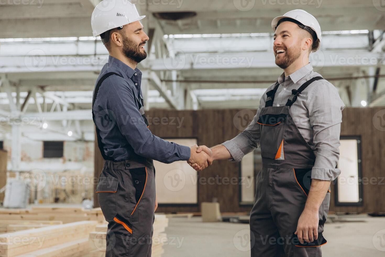 Construction workers shaking hands at modular building factory photo