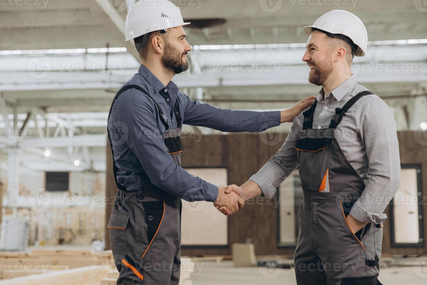 Construction workers shaking hands in modular building factory photo