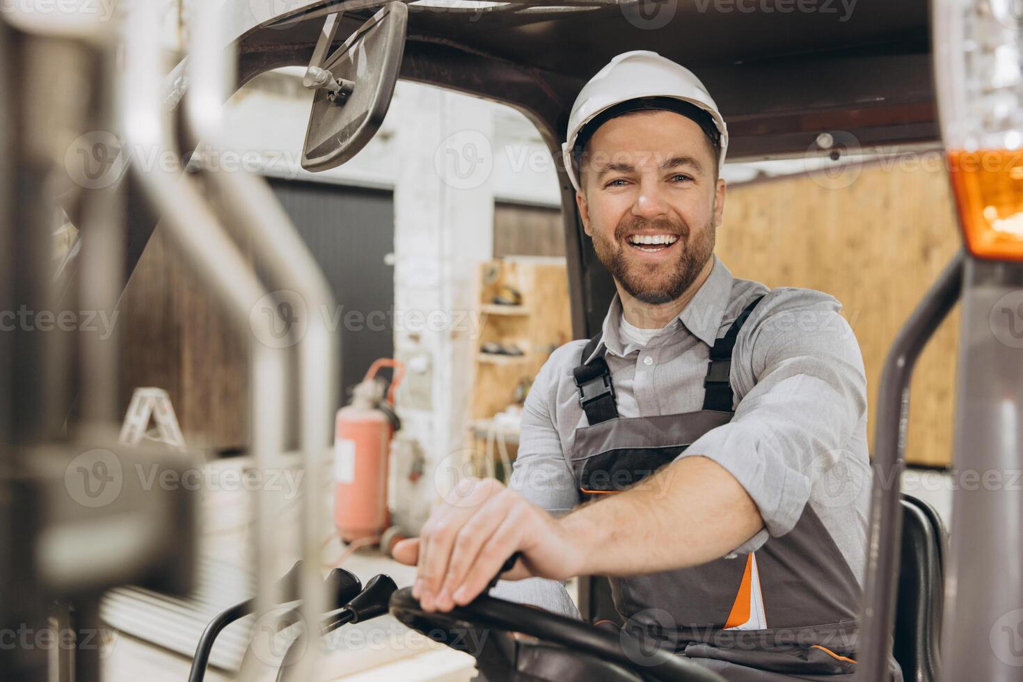 Smiling engineer driving forklift in modular building factory photo