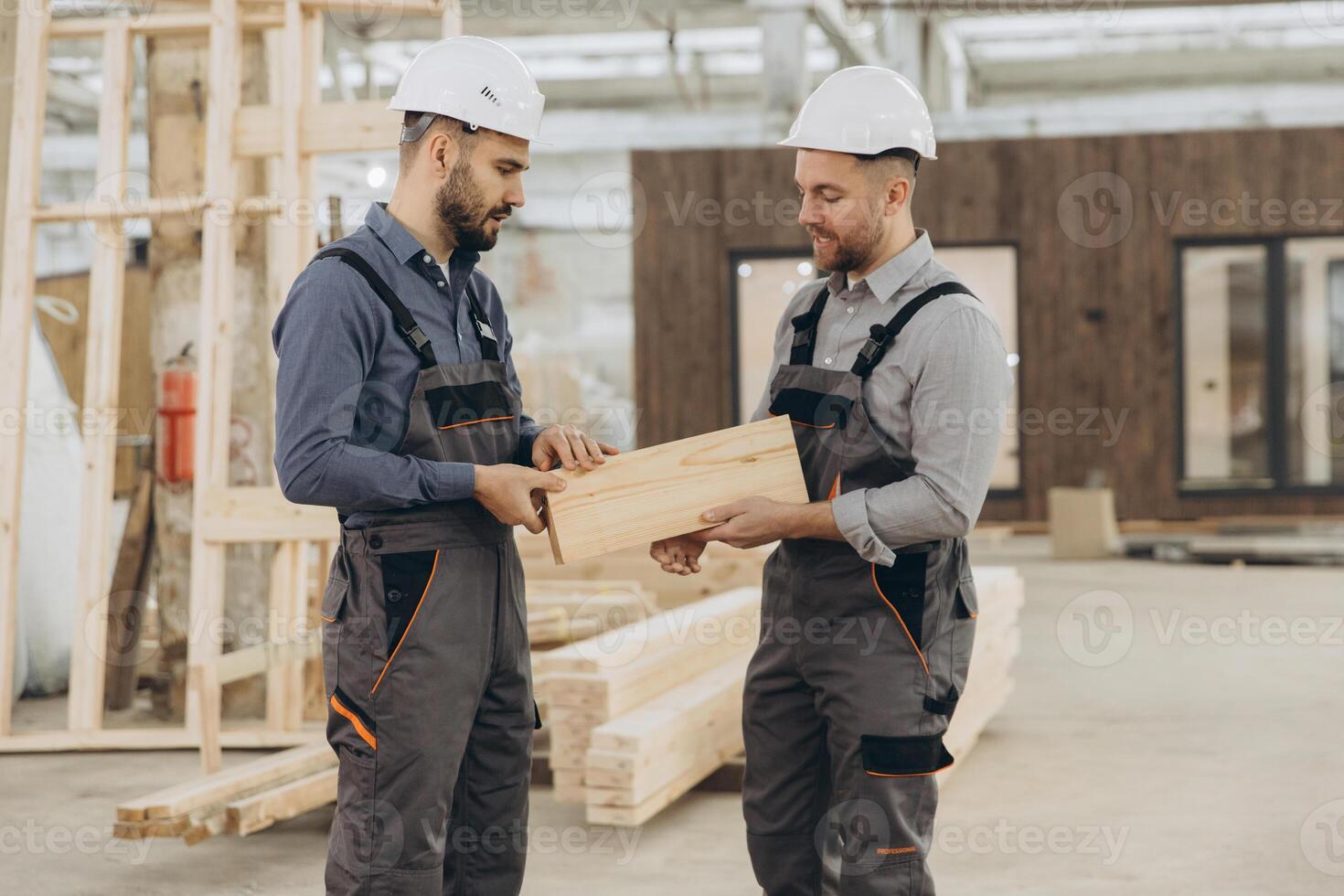 Construction workers examining wooden plank in modular building factory photo