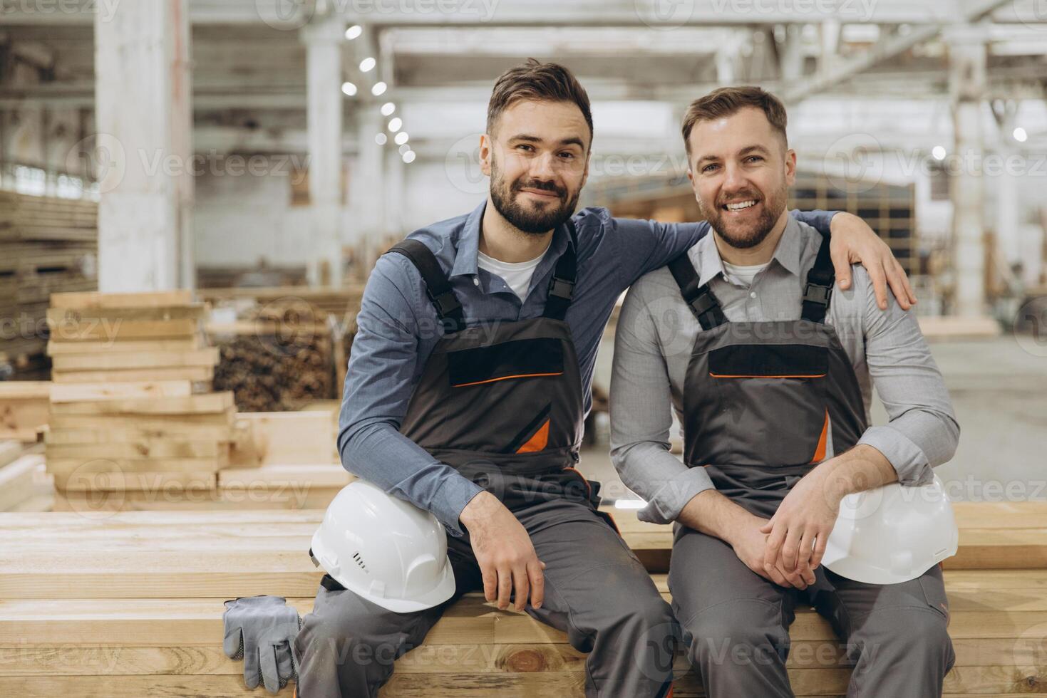 Two carpenters smiling and resting in timber warehouse photo