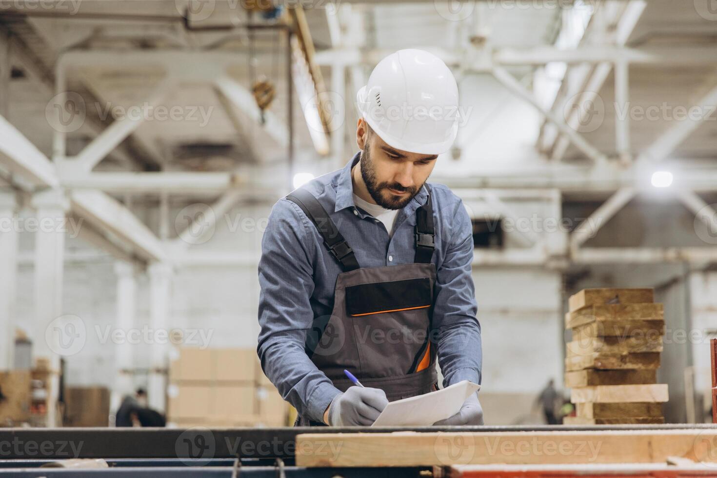 Supervisor writing on clipboard, inspecting wood in modular building factory photo