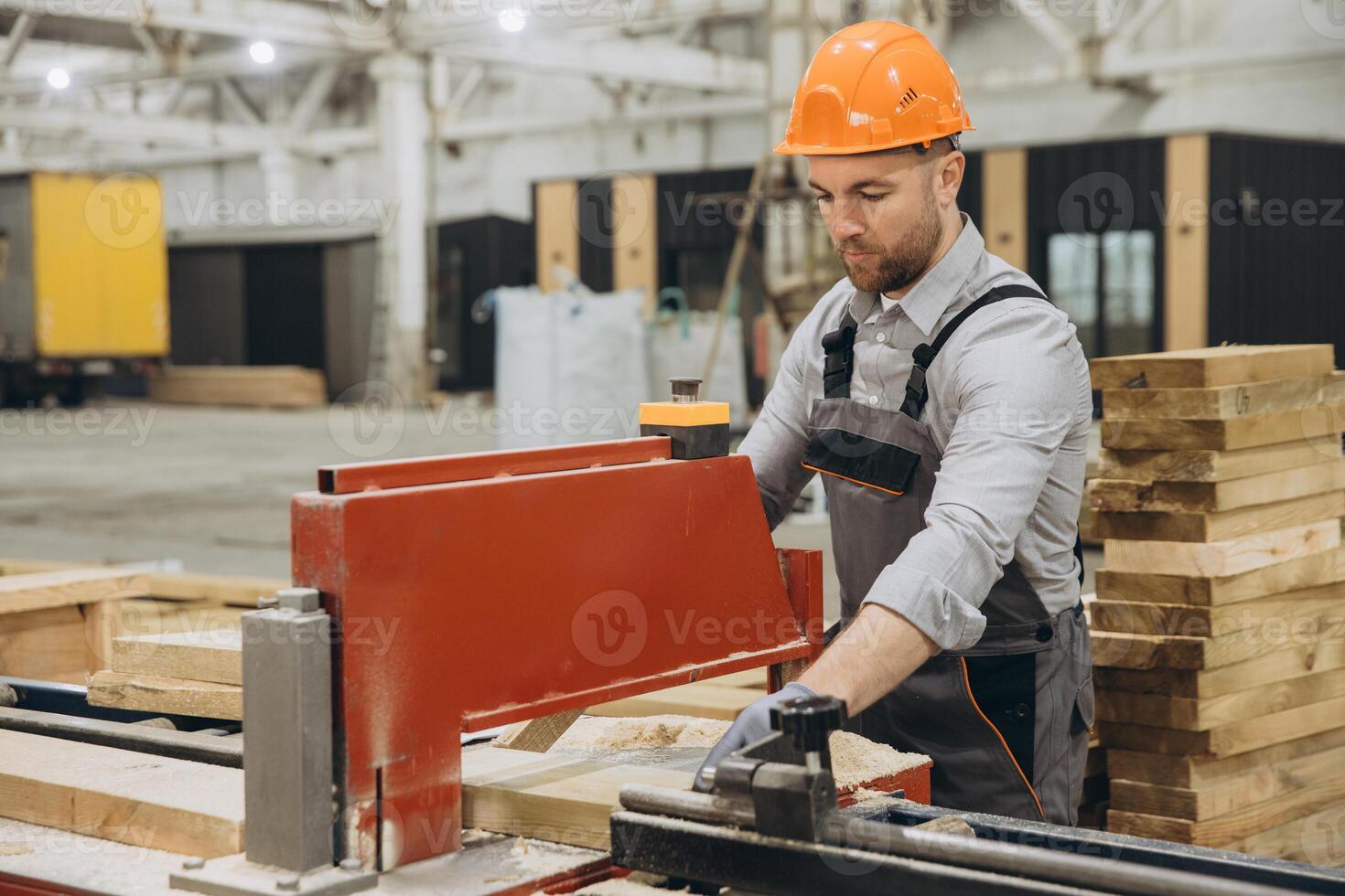 Carpenter working with wood plank and precision saw in workshop for modular building industry photo