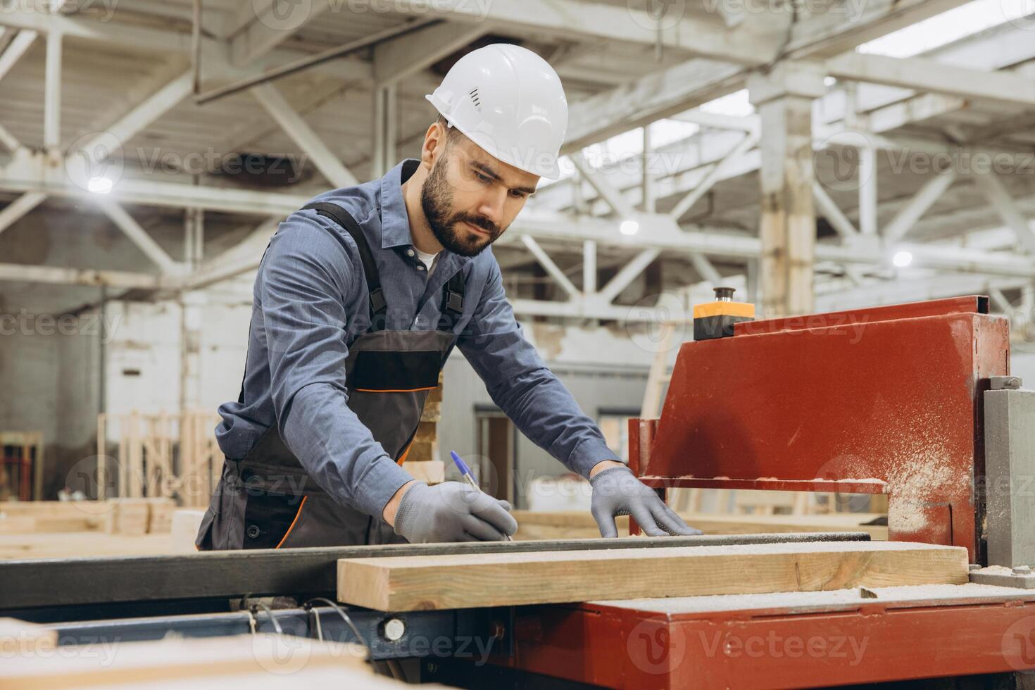 Carpenter measuring wooden plank in modular building factory photo