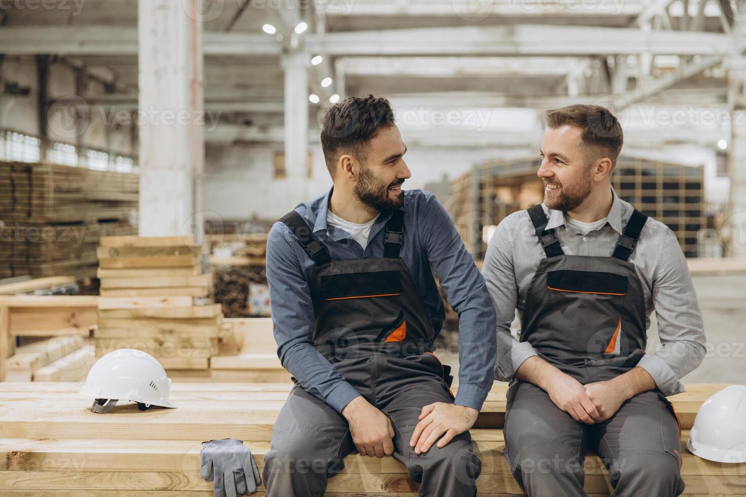 Two carpenters discussing in lumber warehouse of modular building industry photo