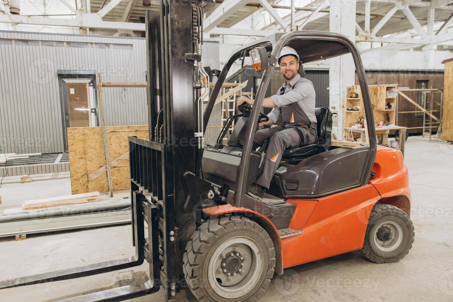 Construction worker driving forklift in modular building factory photo