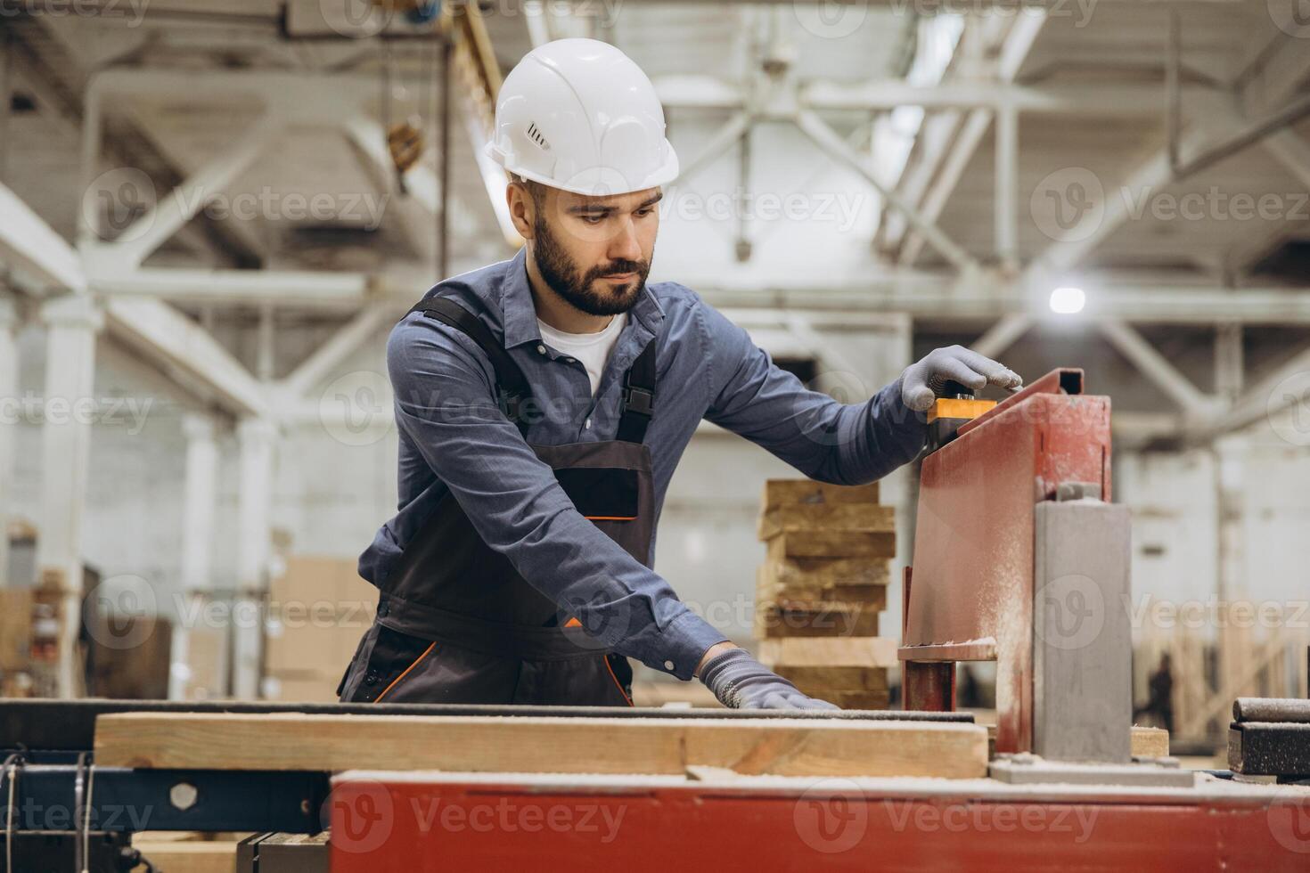 Carpenter working with wood plank and saw in factory for modular building photo
