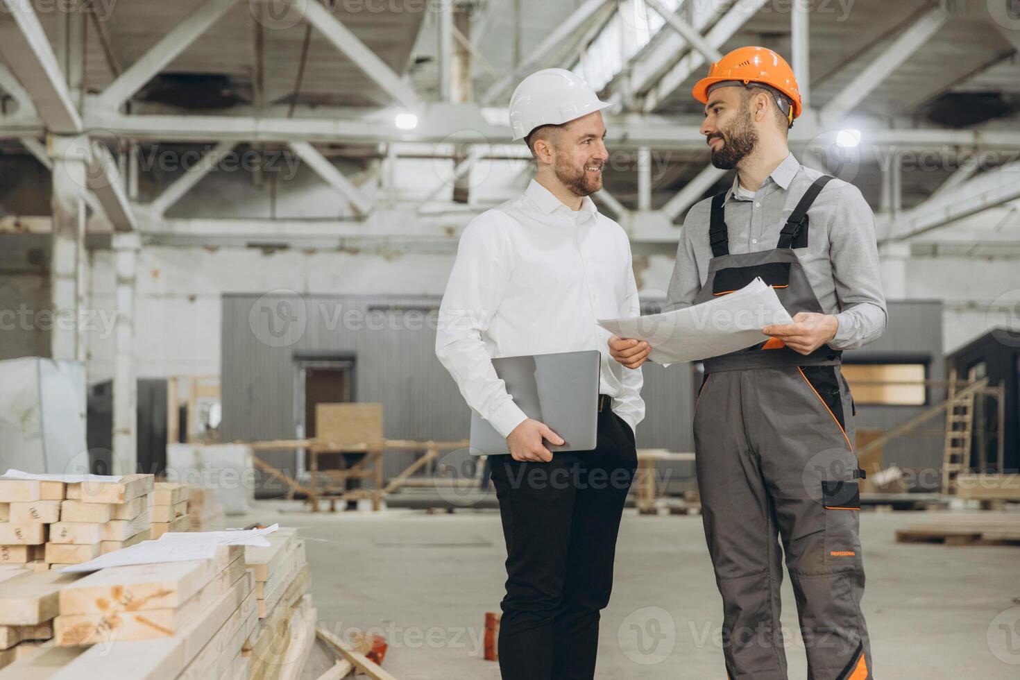 Architect and construction worker discussing plans in modular building factory photo