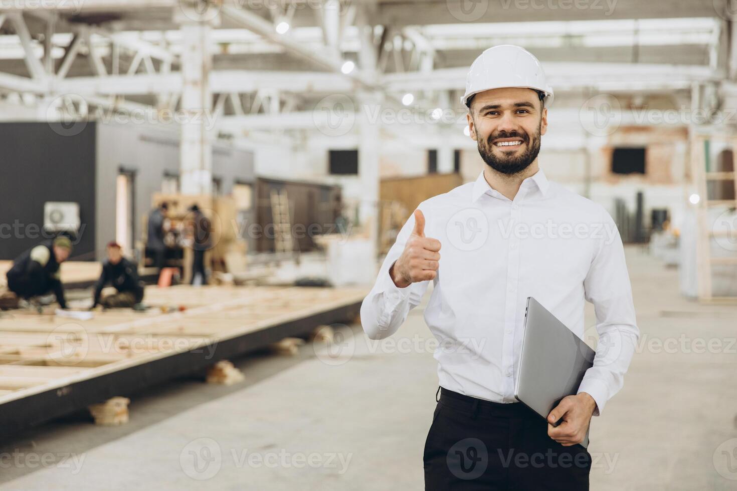 Smiling engineer gesturing thumbs up in modular building factory photo