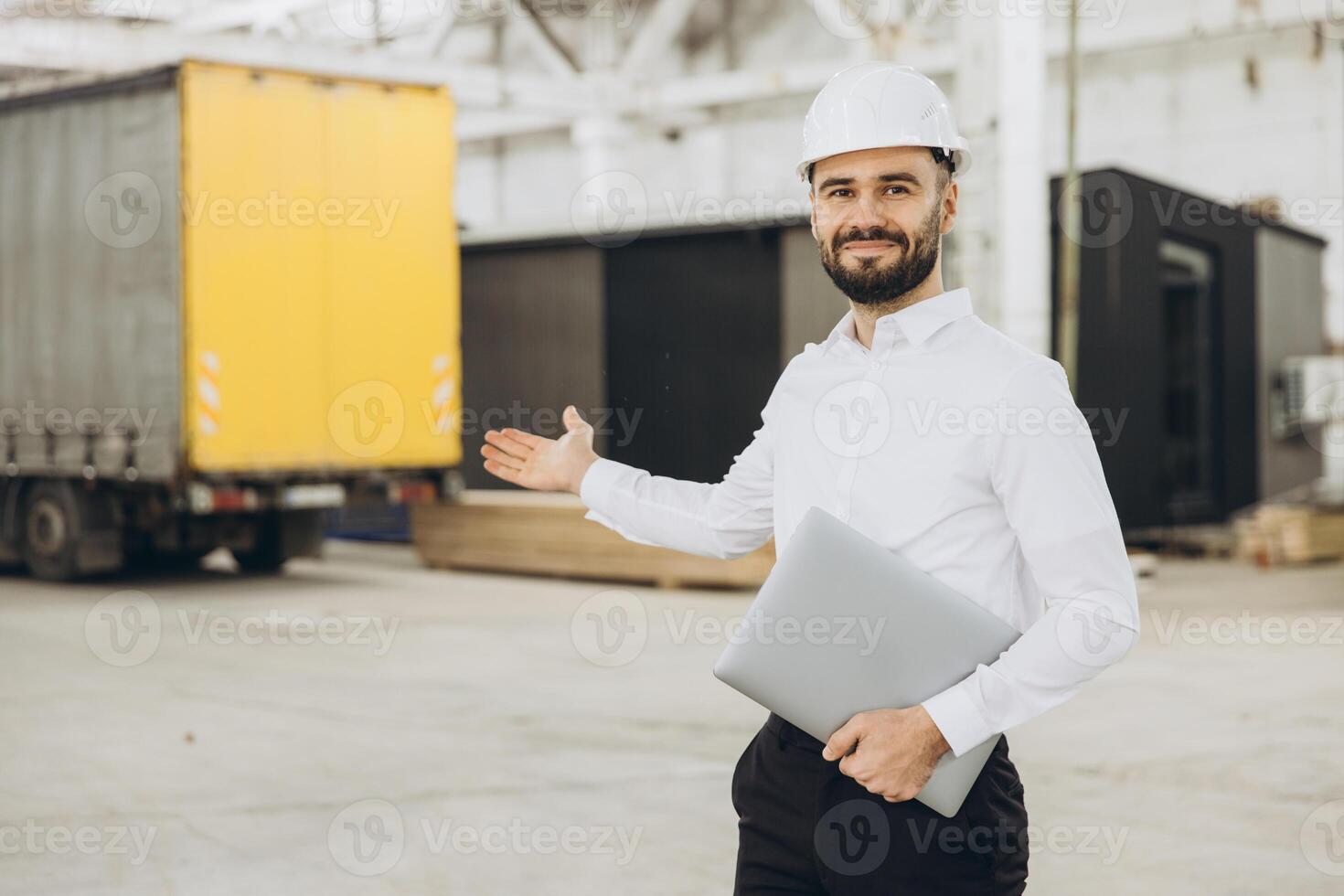 Engineer holding laptop showing prefabricated modules in factory photo