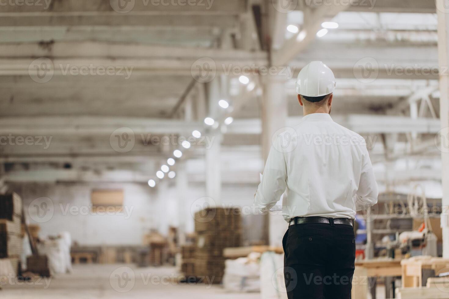 Engineer walking in modular building factory inspecting construction materials photo