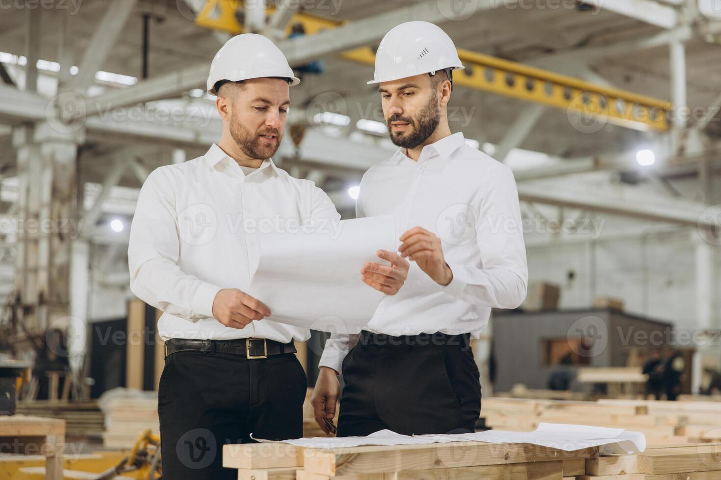 Engineers discussing blueprint in modular building factory photo