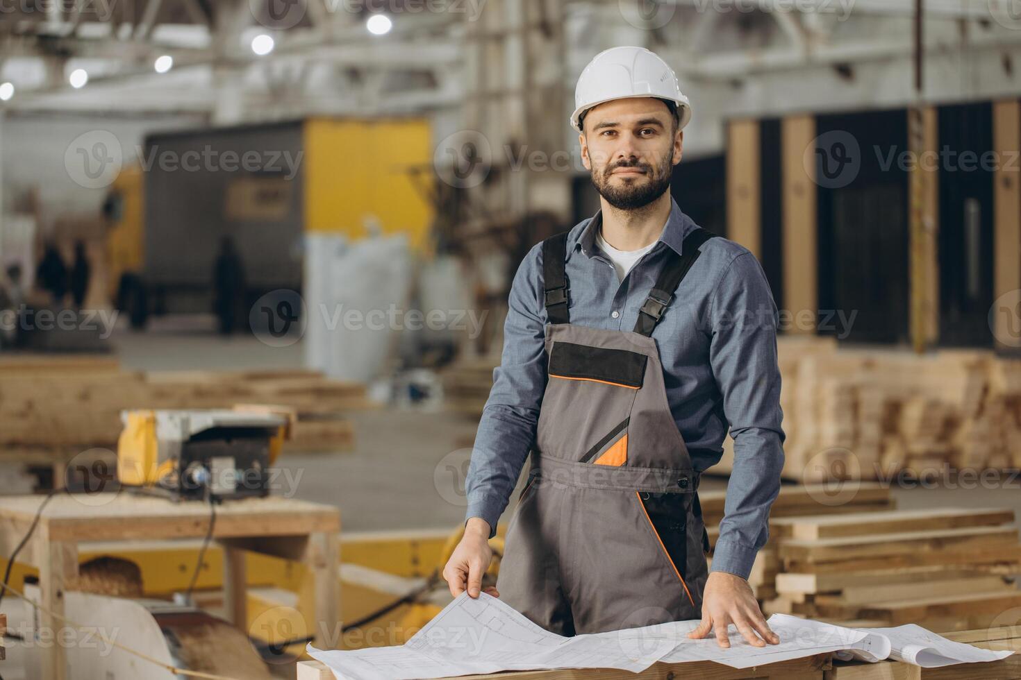 Construction worker examining blueprints in modular building factory photo