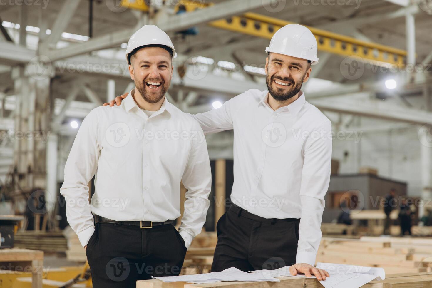 Smiling engineers discussing plans in modular building factory photo