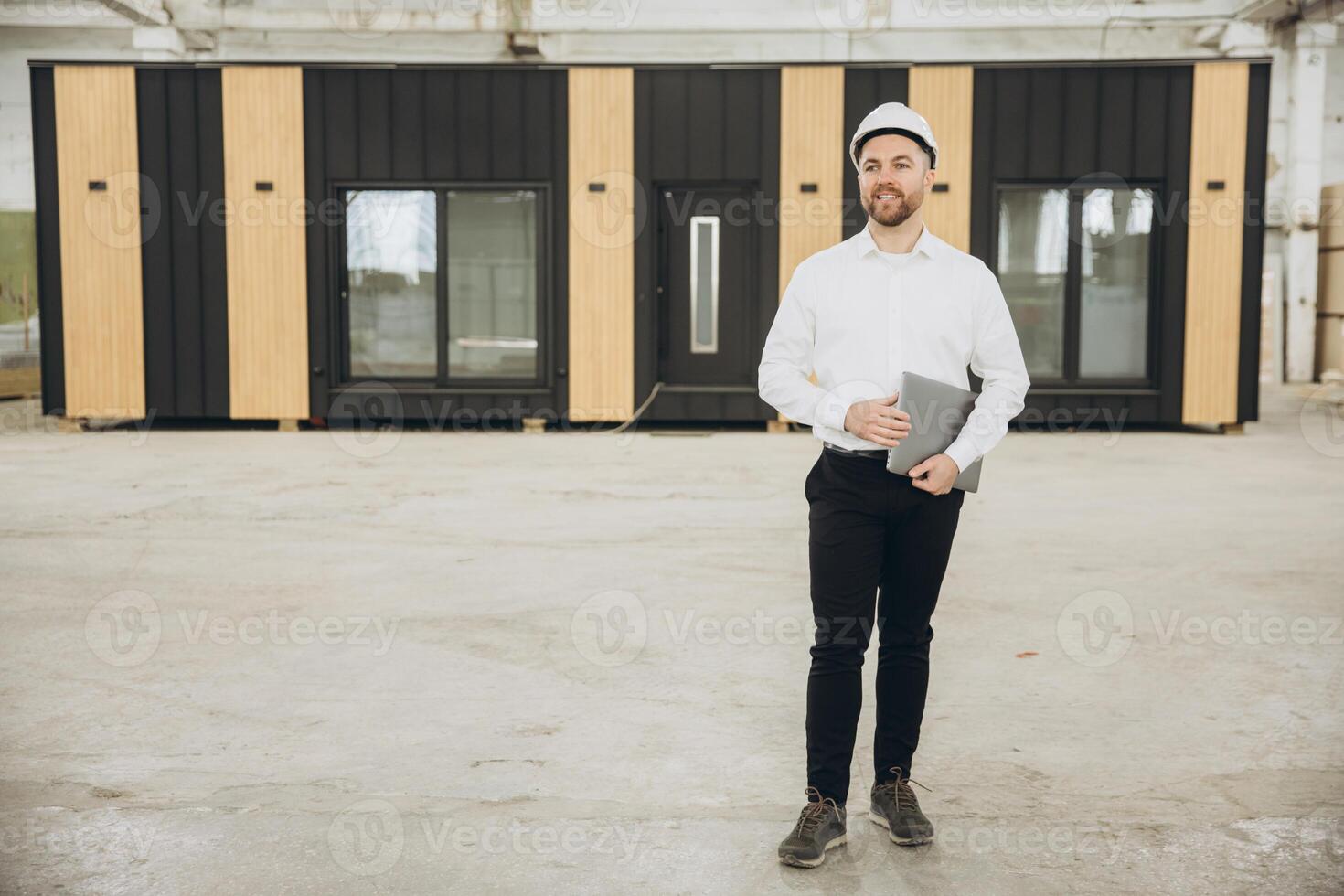 Architect holding laptop supervising prefabricated modular building construction photo