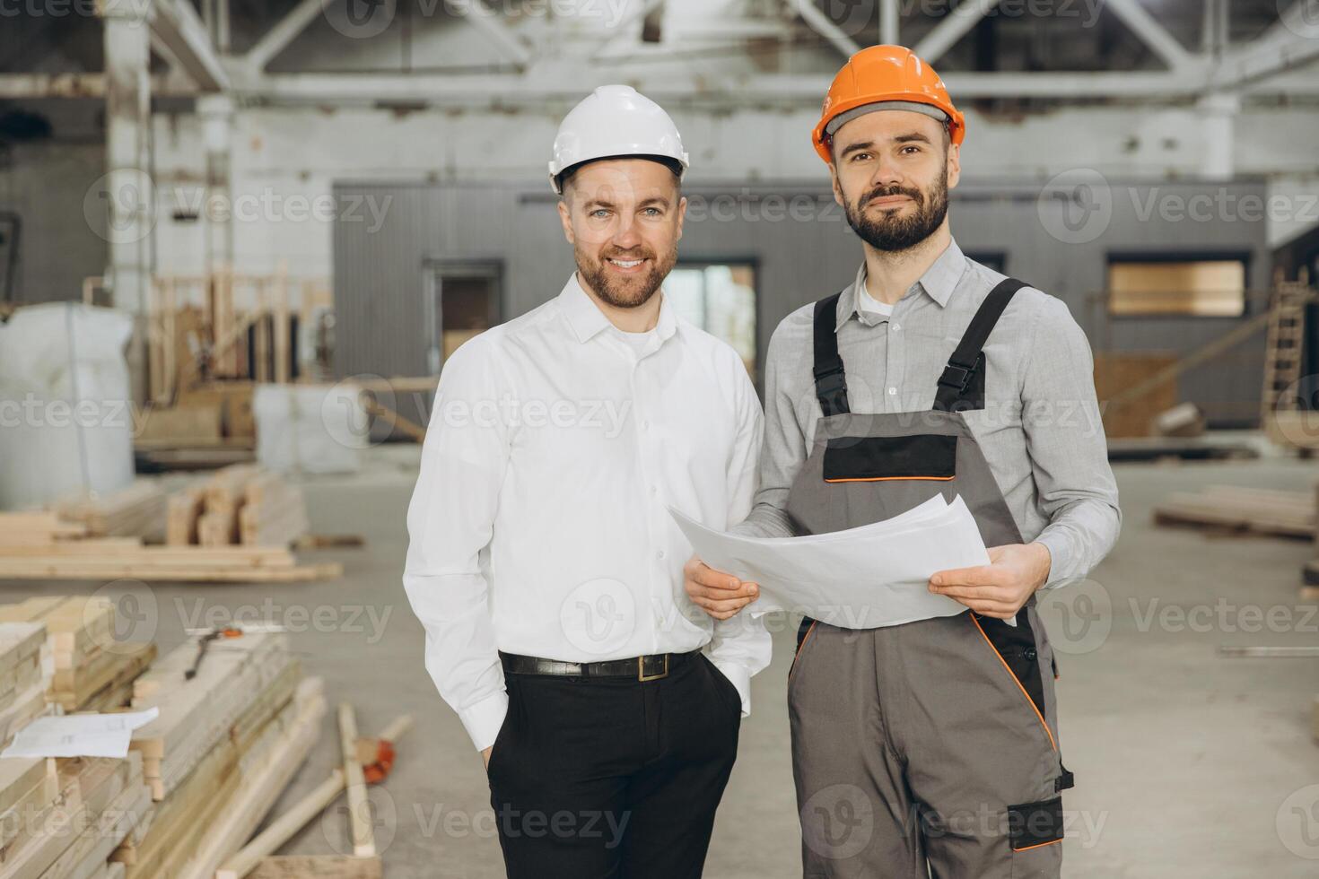 Architect and construction worker discussing plans in modular building factory photo