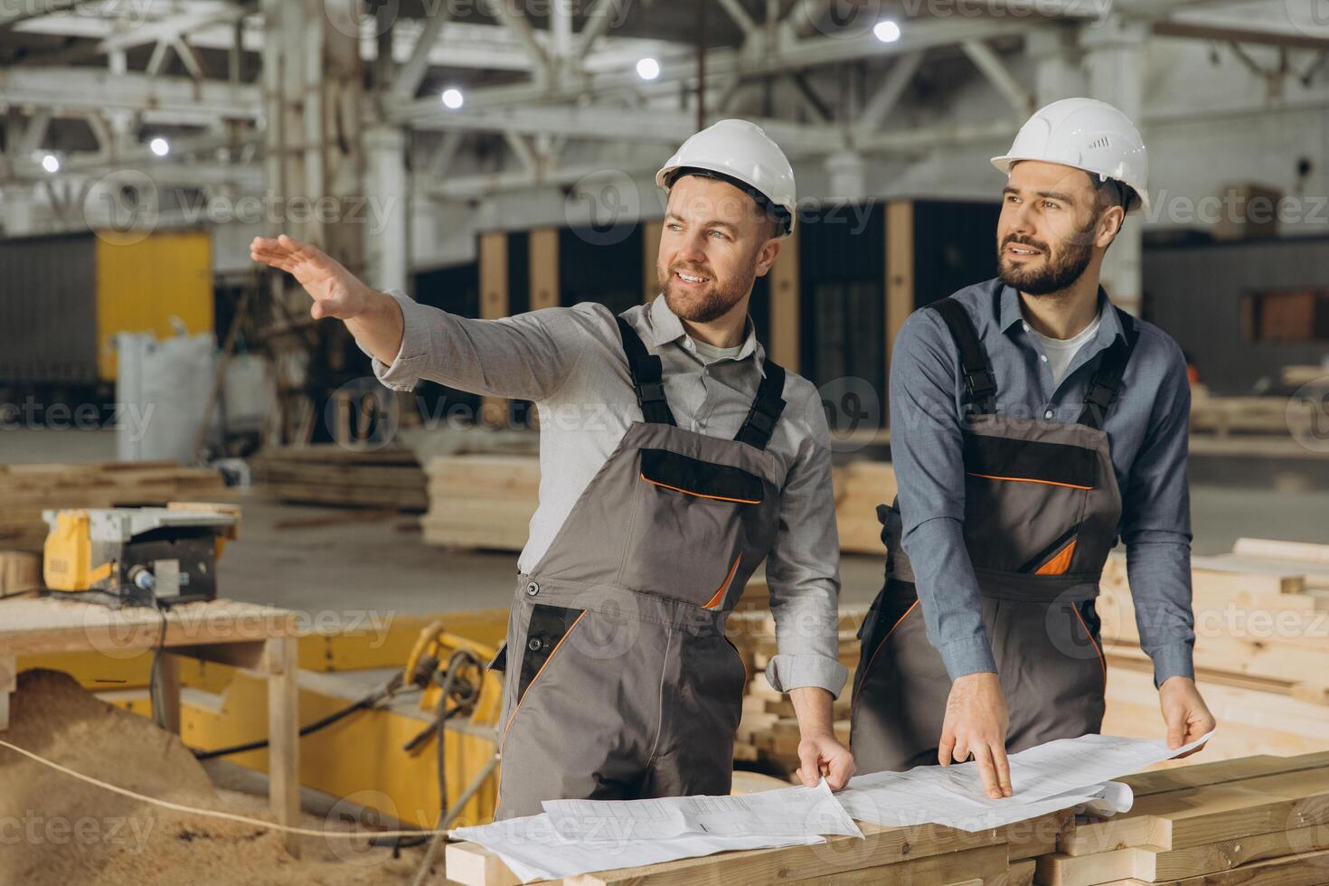 Engineers discussing building project using blueprint in modular house factory photo