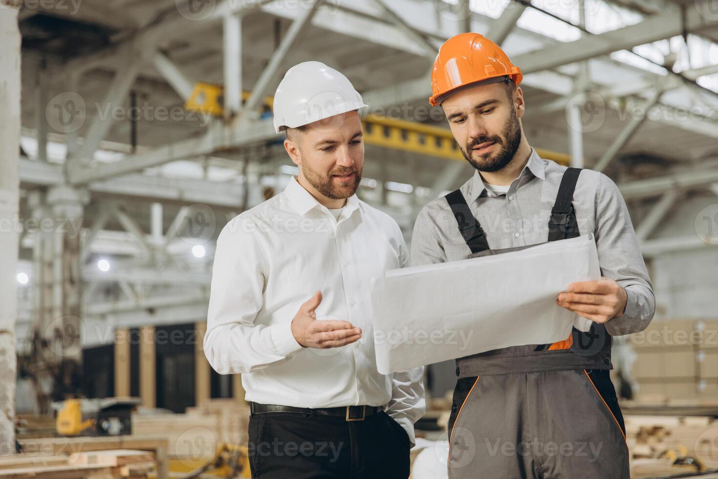 Engineers discussing blueprint in modular building factory photo