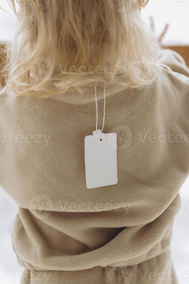 Child wearing fleece suit with blank clothing label mockup photo