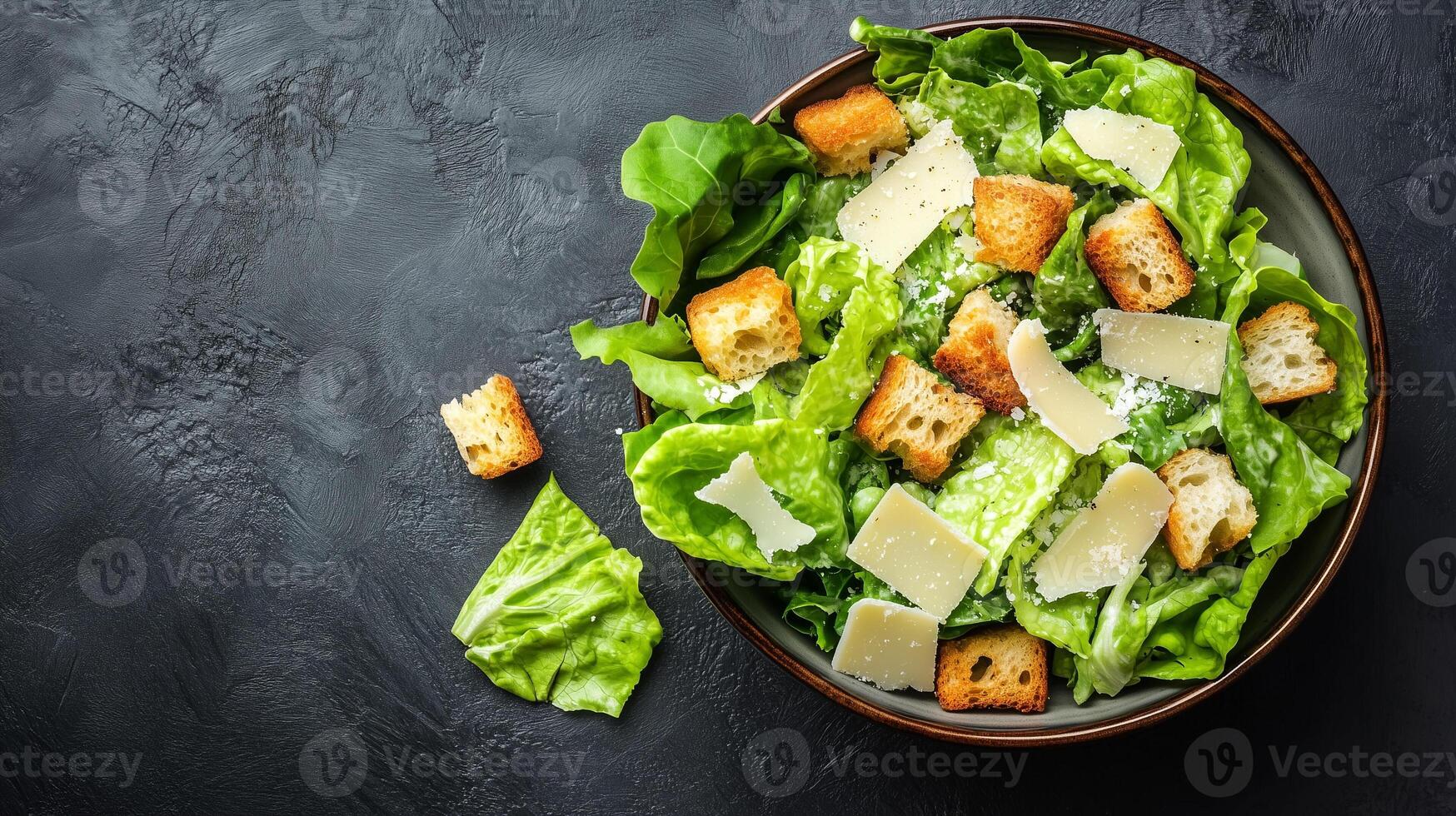Caesar salad assembled with romaine lettuce, croutons, parmesan cheese, and Caesar dressing in a bowl, food setting photo